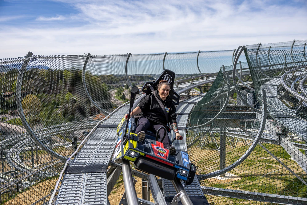 rider on Pigeon Forge Racing Coaster with Pigeon Forge and mountain view in background